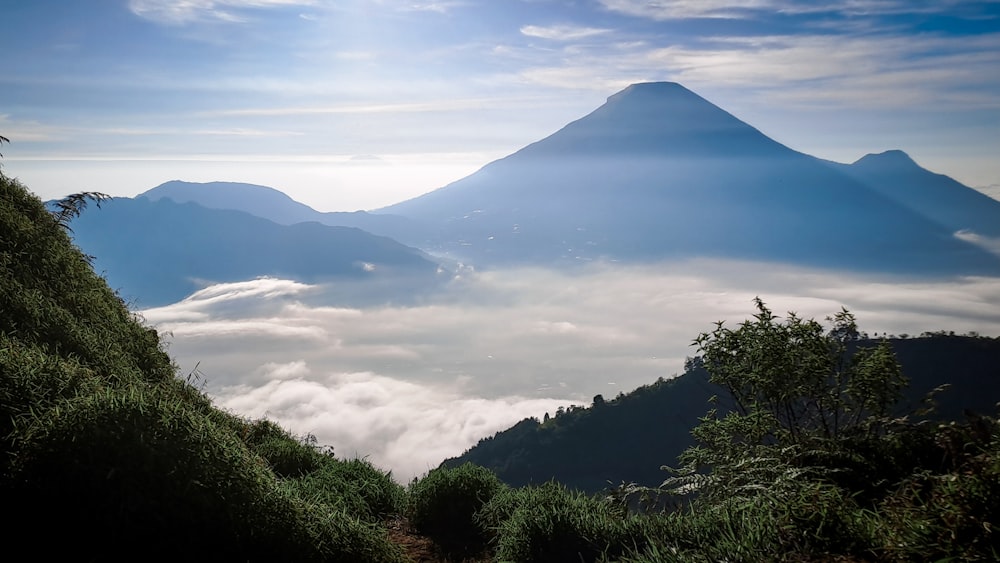 a view of a mountain with clouds and trees