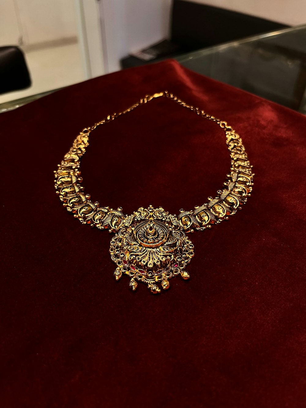 a gold necklace on a red velvet table