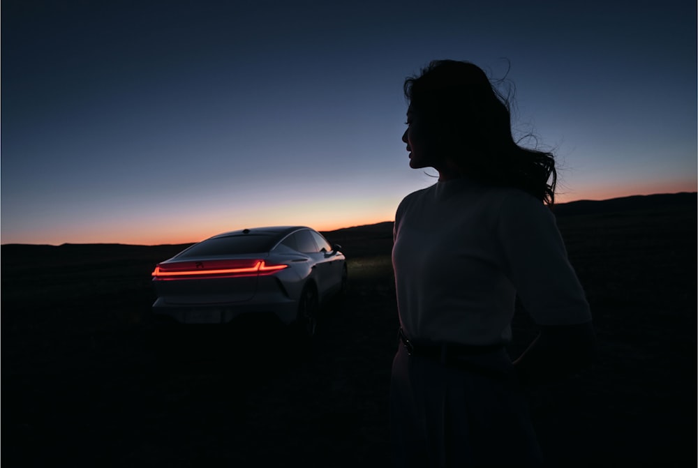 a woman standing next to a car in the dark