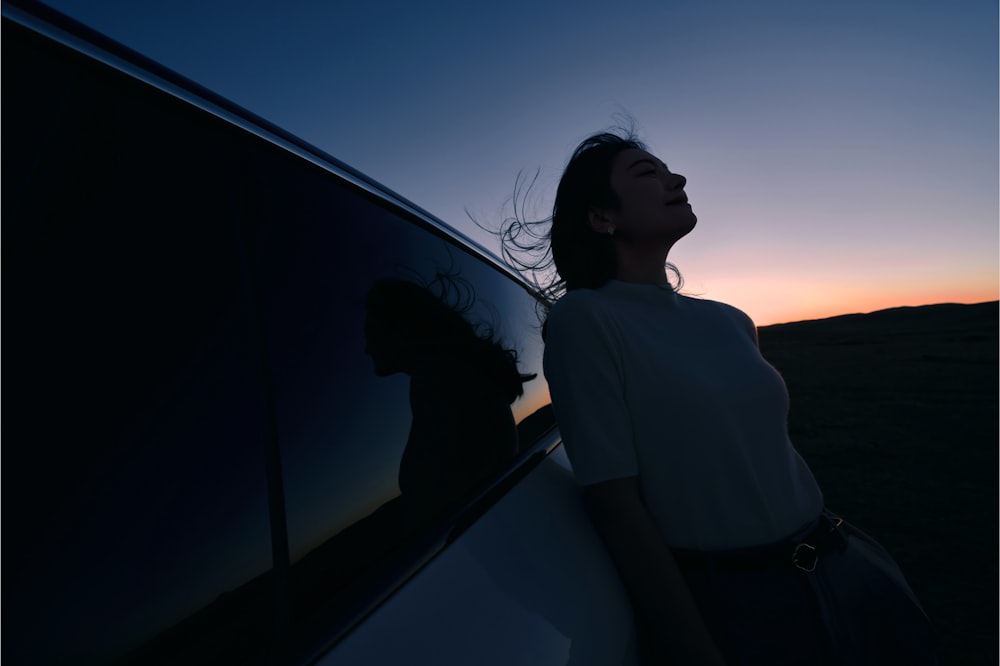 a woman standing next to a car at sunset