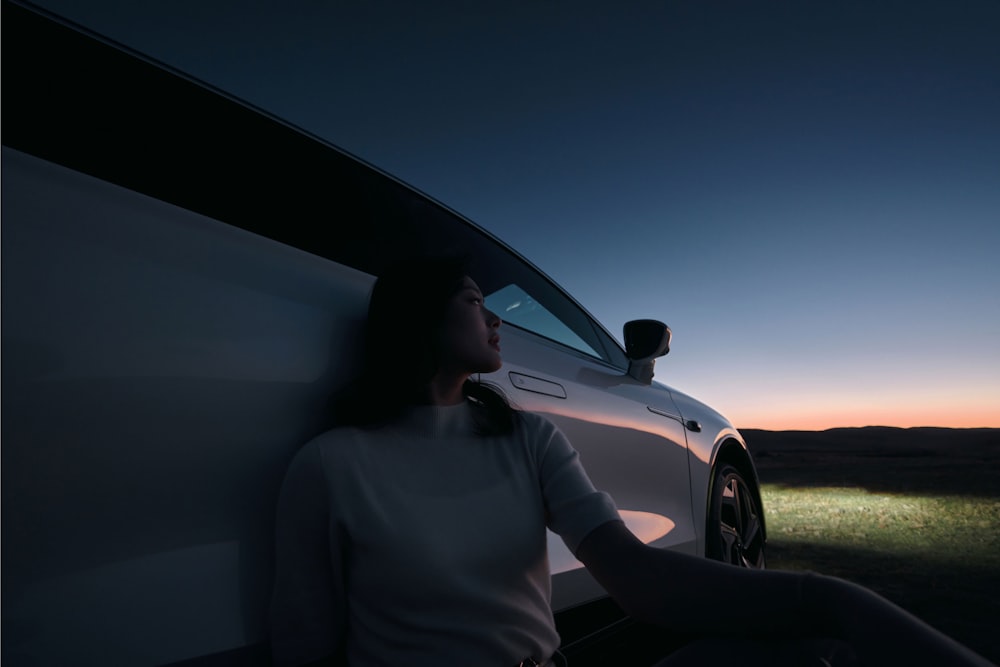 a woman leaning against the side of a car