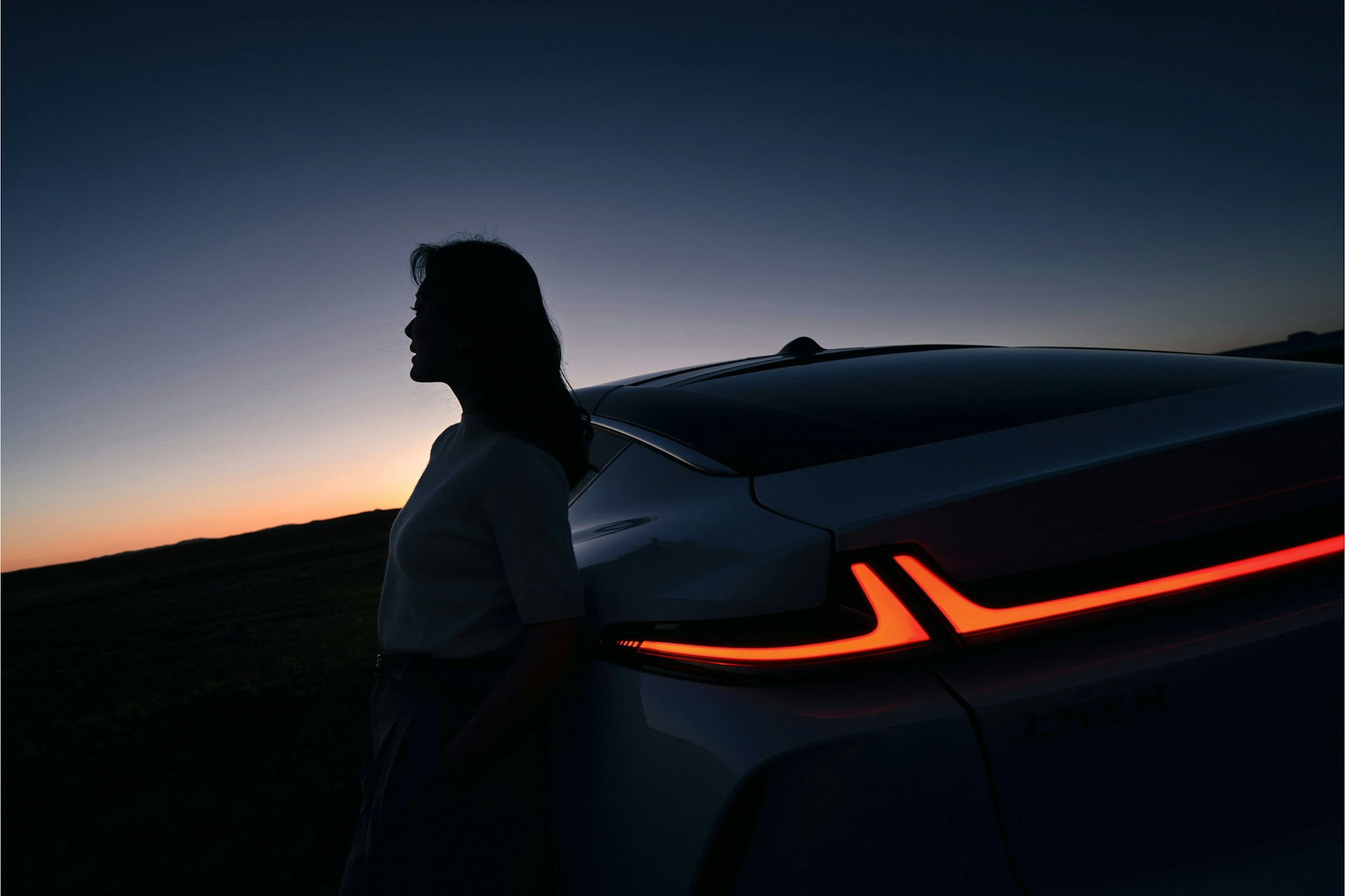 a woman standing next to a car at sunset