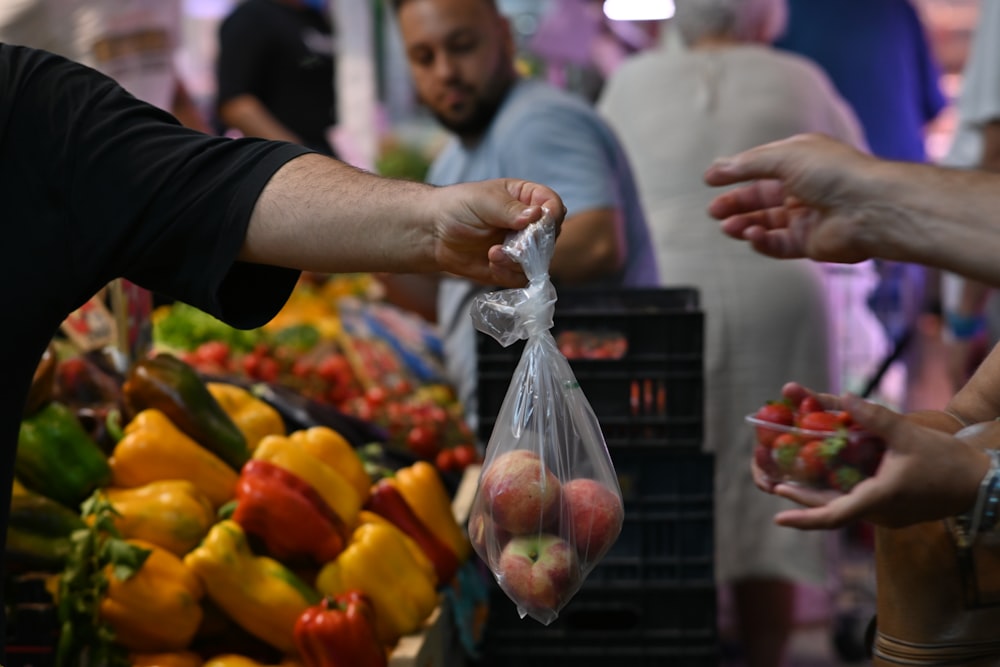 a group of people standing around a fruit stand