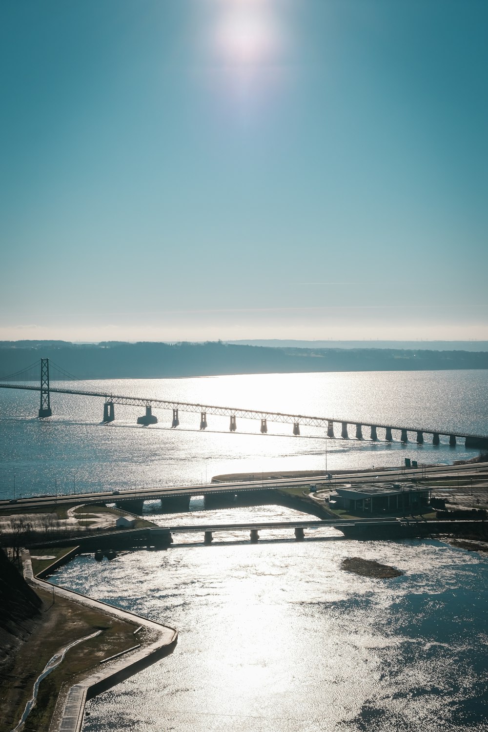 the sun is shining over the water and a bridge