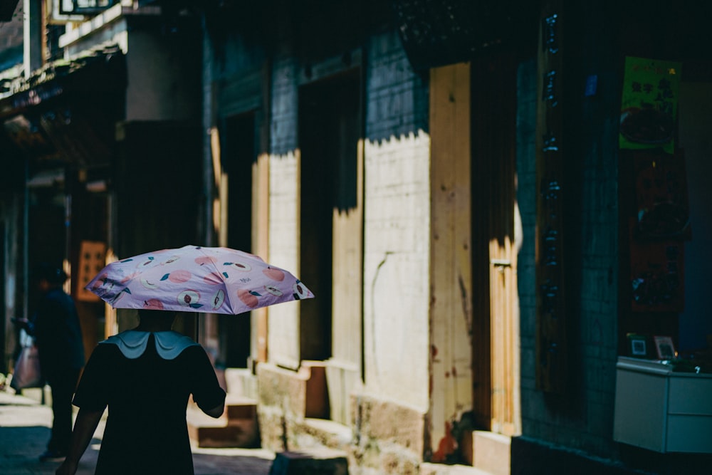eine Frau, die mit einem Regenschirm in der Hand eine Straße entlanggeht