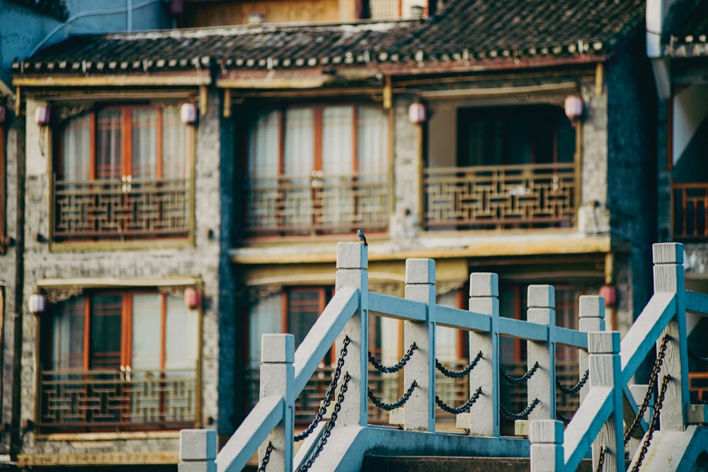 a bird sitting on a railing in front of a building