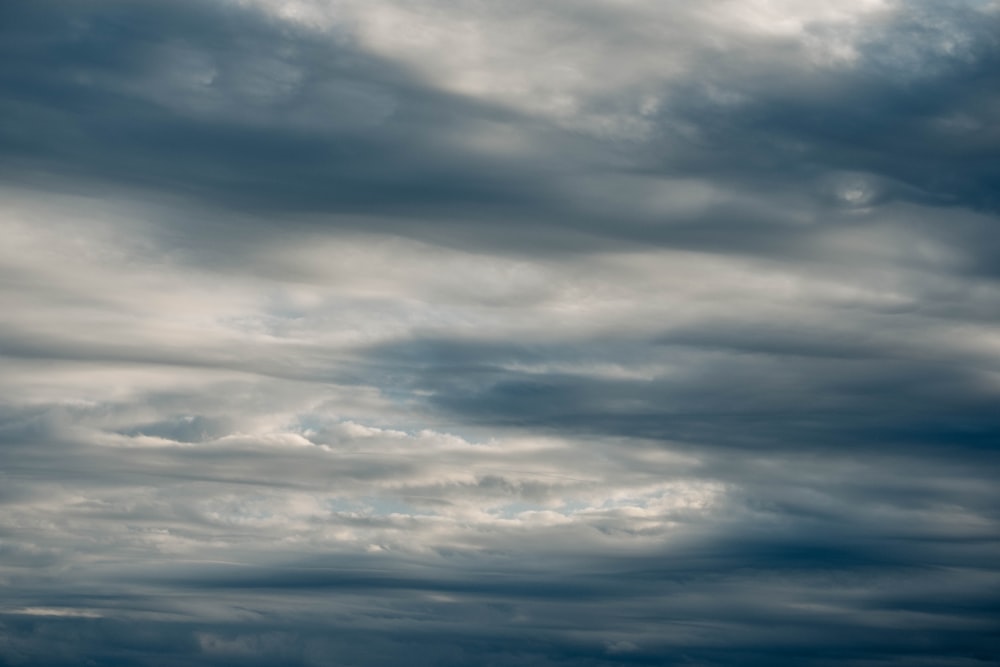 a plane flying through a cloudy blue sky