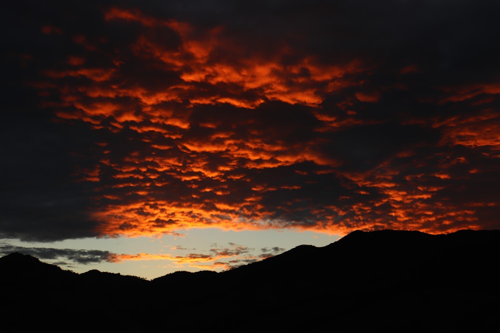 um pôr do sol com nuvens e montanhas ao fundo