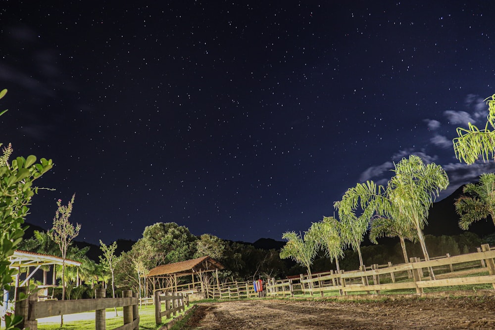 a night time scene of a farm with a fence and trees