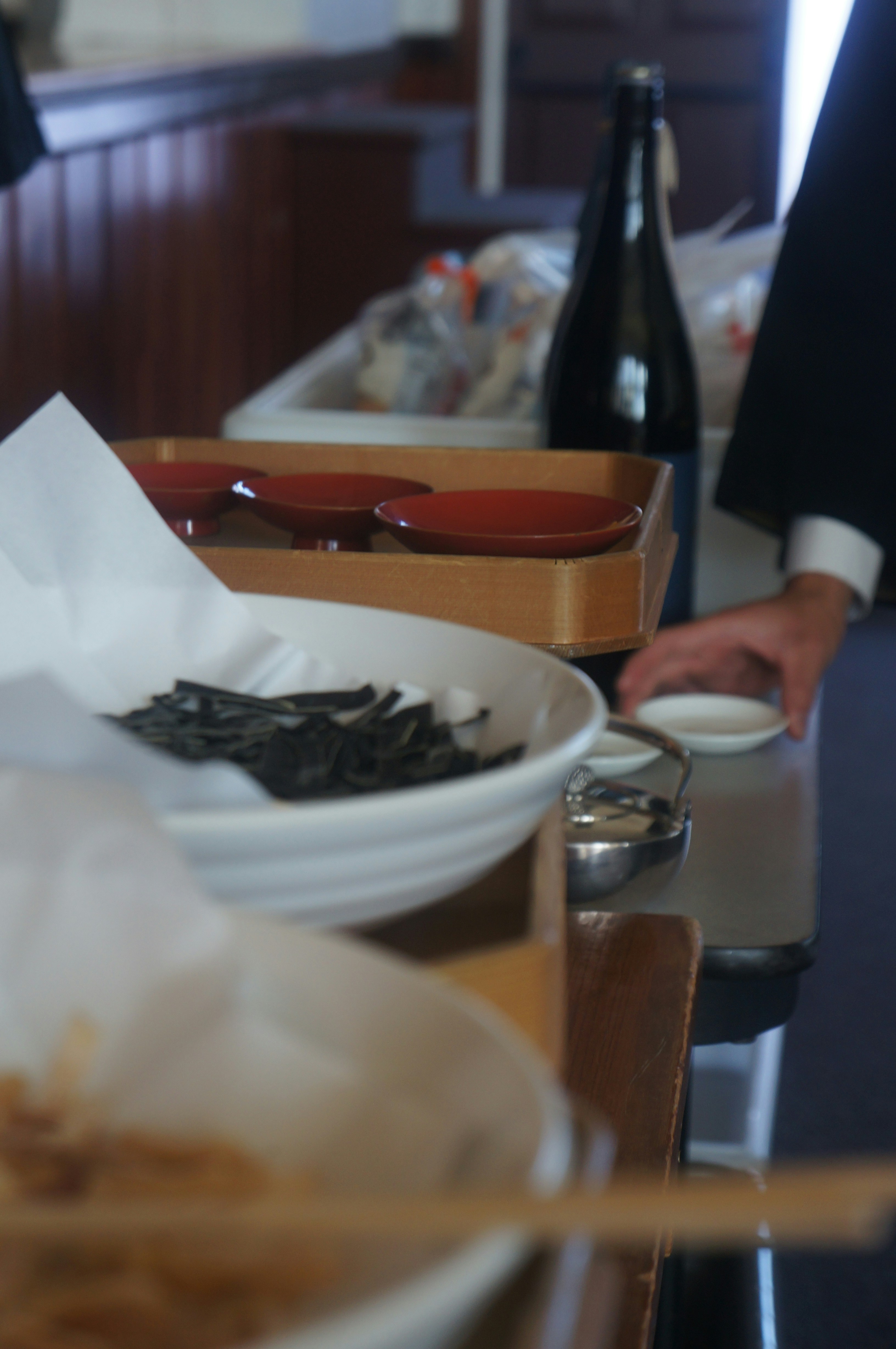 a table with a bowl of noodles and a bottle of wine