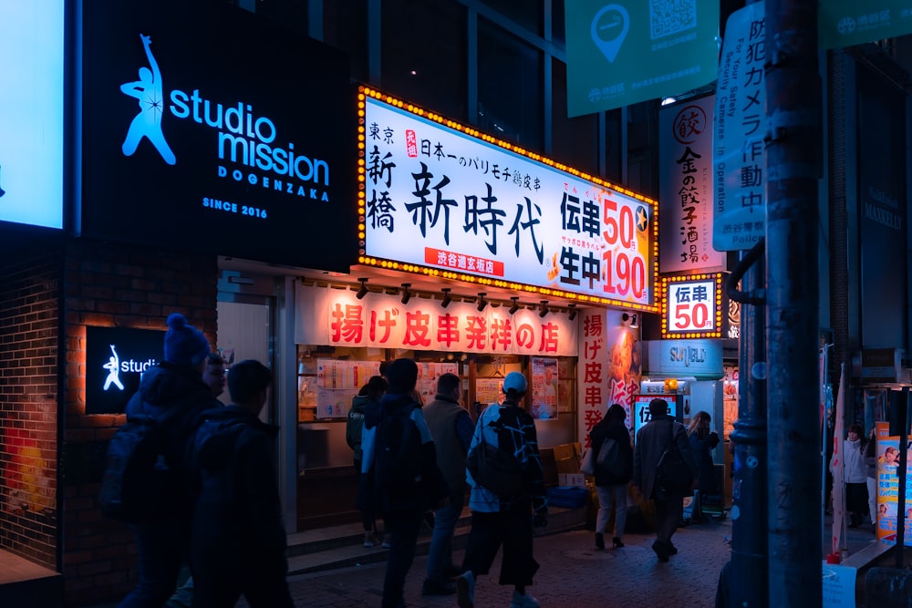 a group of people walking down a street at night