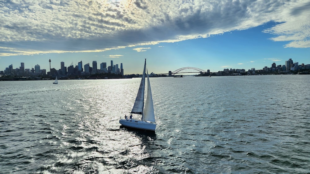 a sailboat in the water with a city in the background