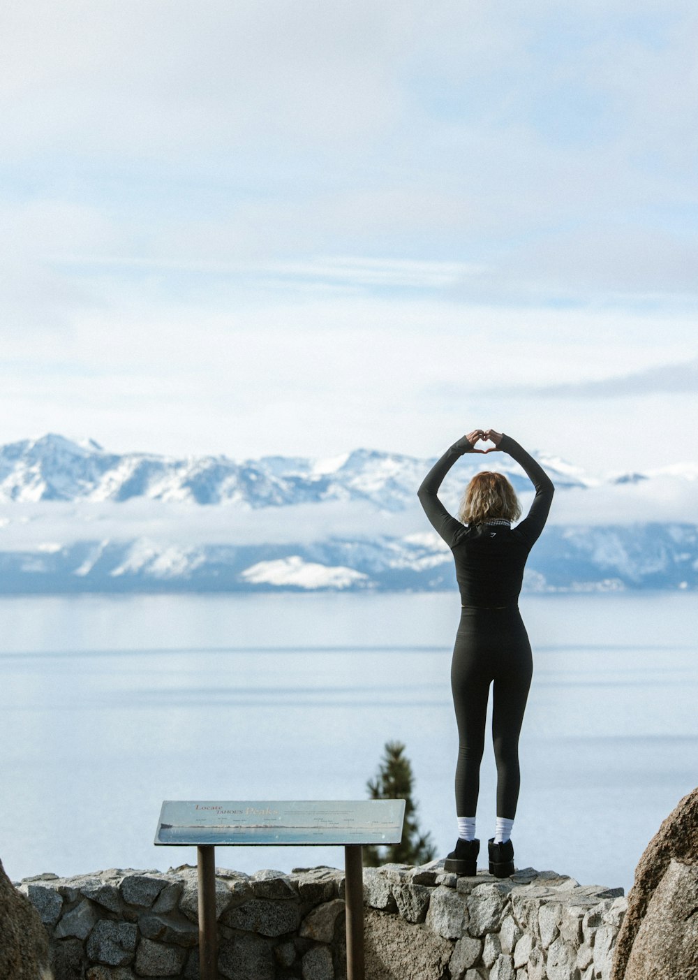 a woman standing on top of a stone wall