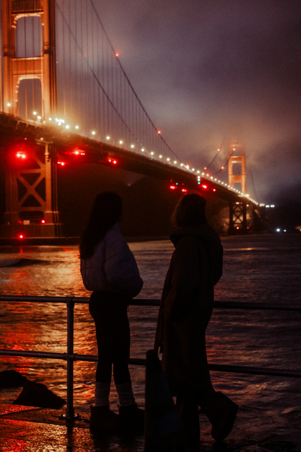 a couple of people standing next to each other near a bridge