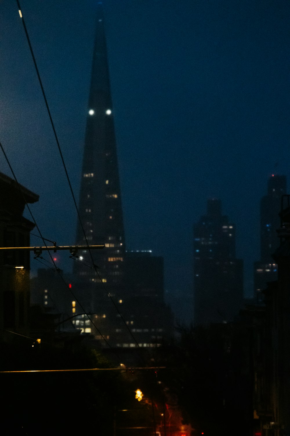 a city street at night with a very tall building in the background