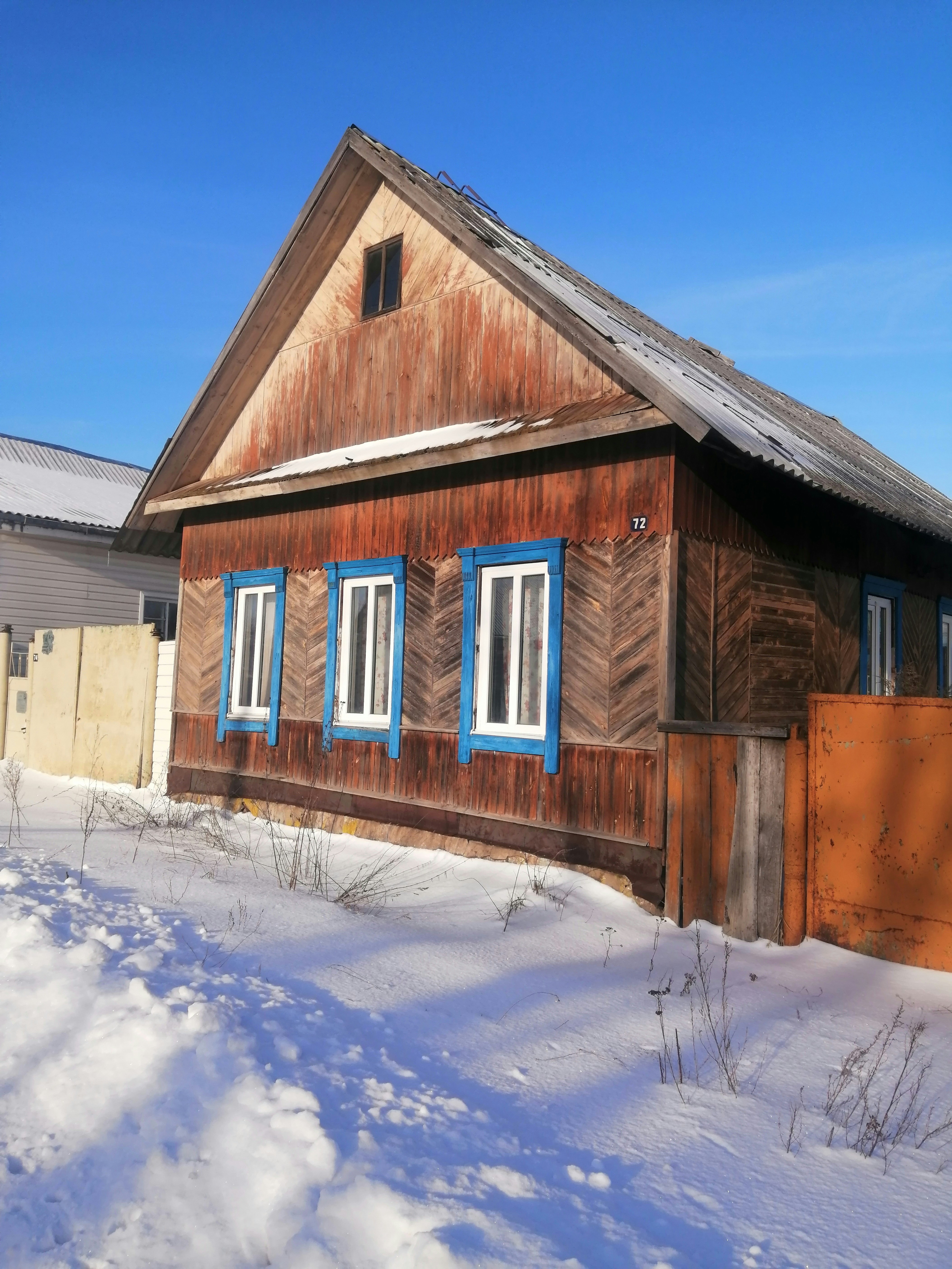 uma casa de madeira com janelas azuis na neve