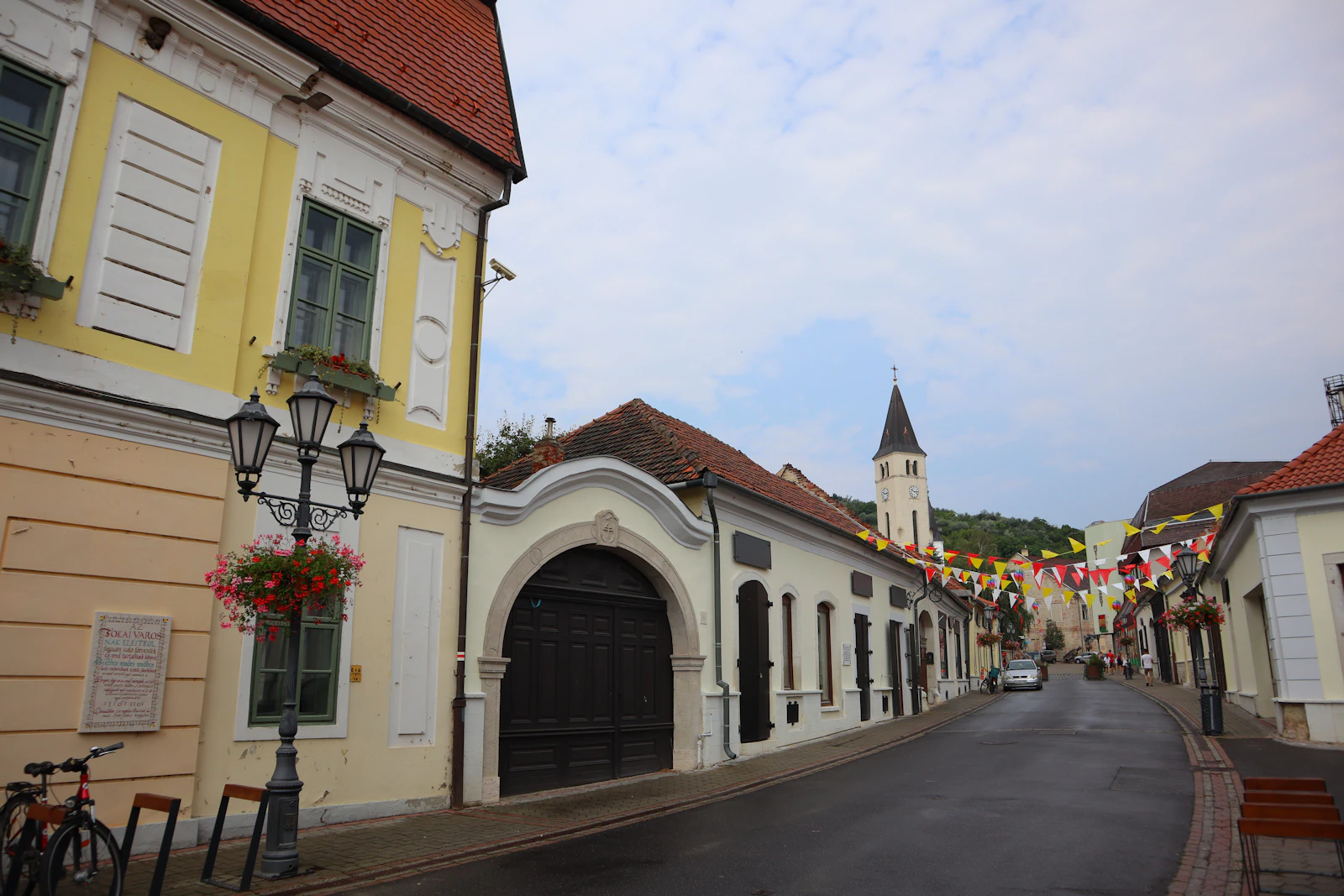 The main street of the town, with the church tower beyond — Tokaj, Hungary