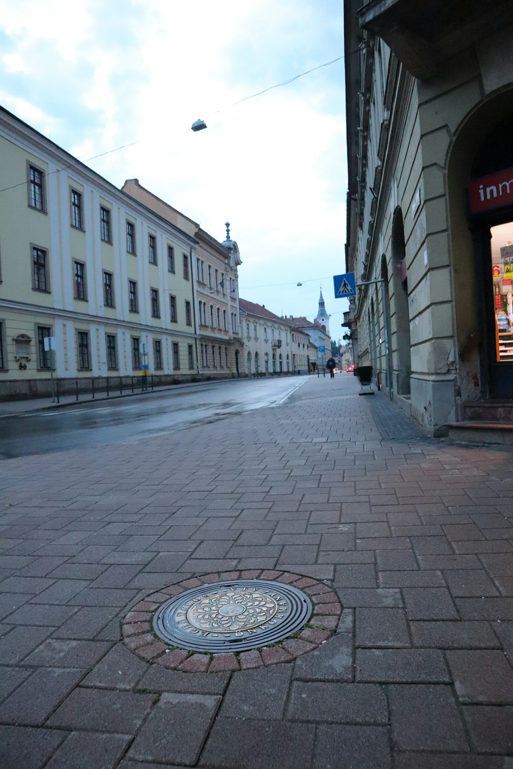 un tombino su una strada di mattoni con edifici sullo sfondo