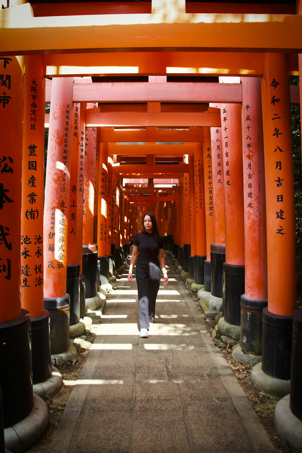 a woman walking down a path lined with orange tori tori tori tori tori tori tori