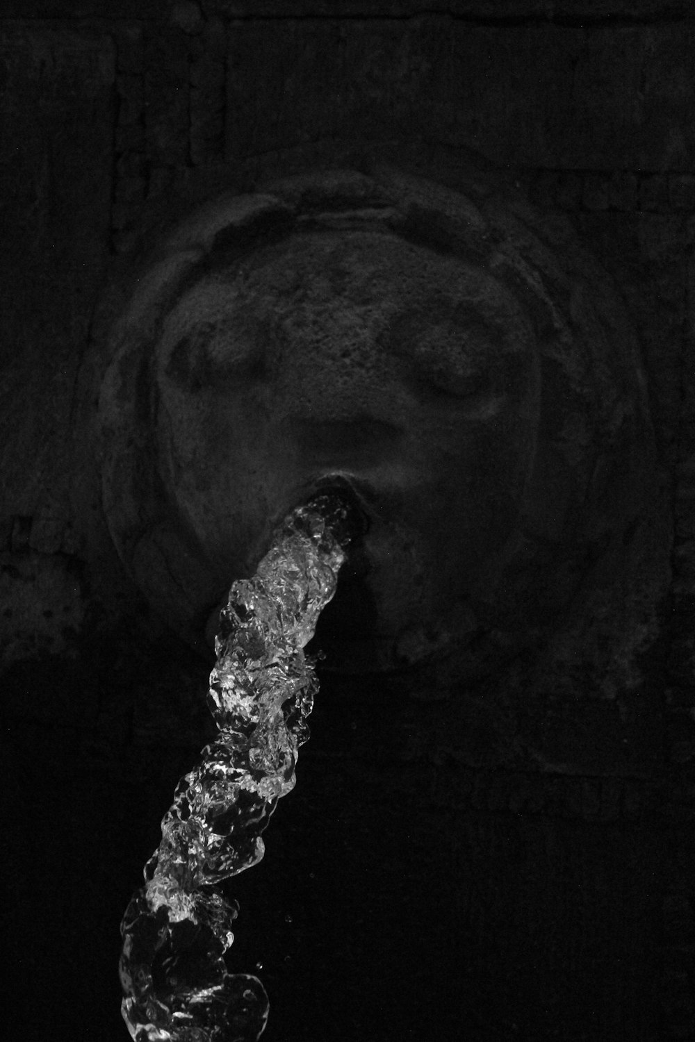a black and white photo of water coming out of a faucet