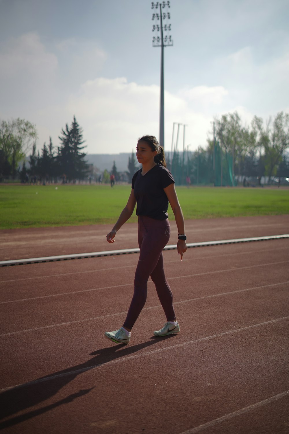 a woman walking across a track in a field