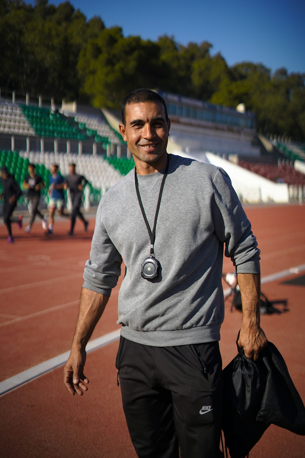 a man walking on a tennis court holding a bag