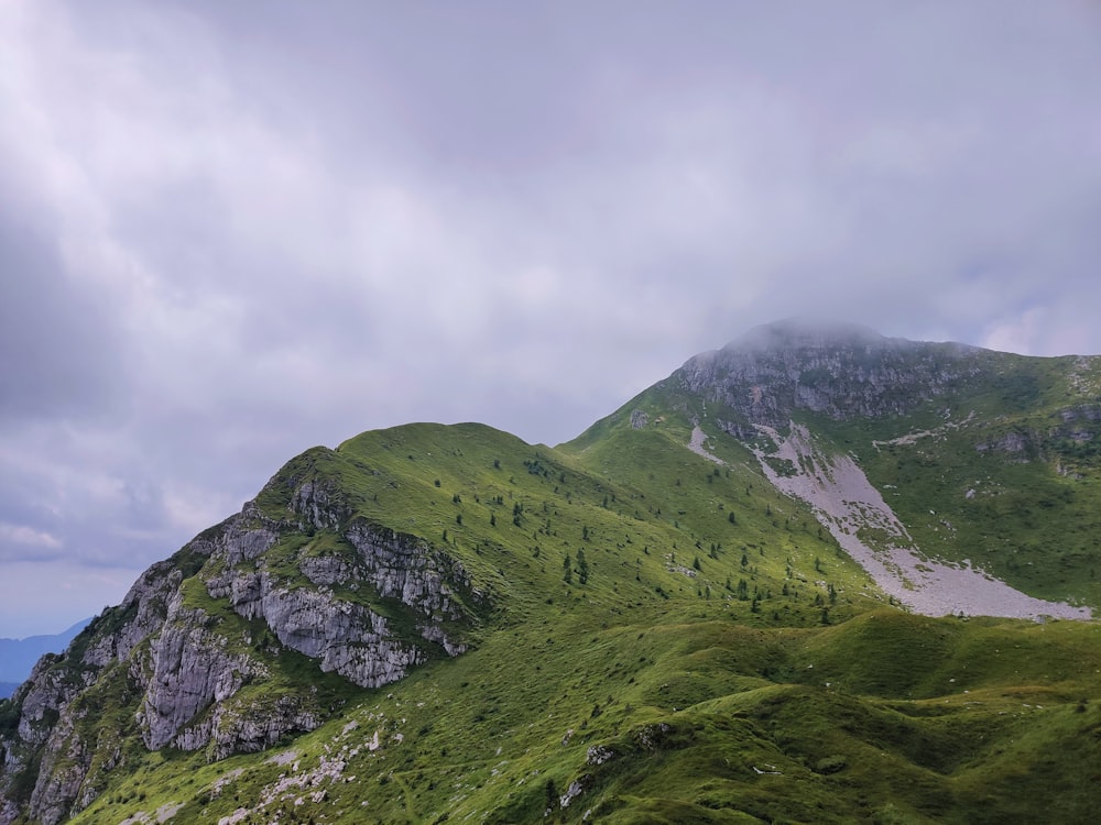 a green mountain with a few clouds in the sky