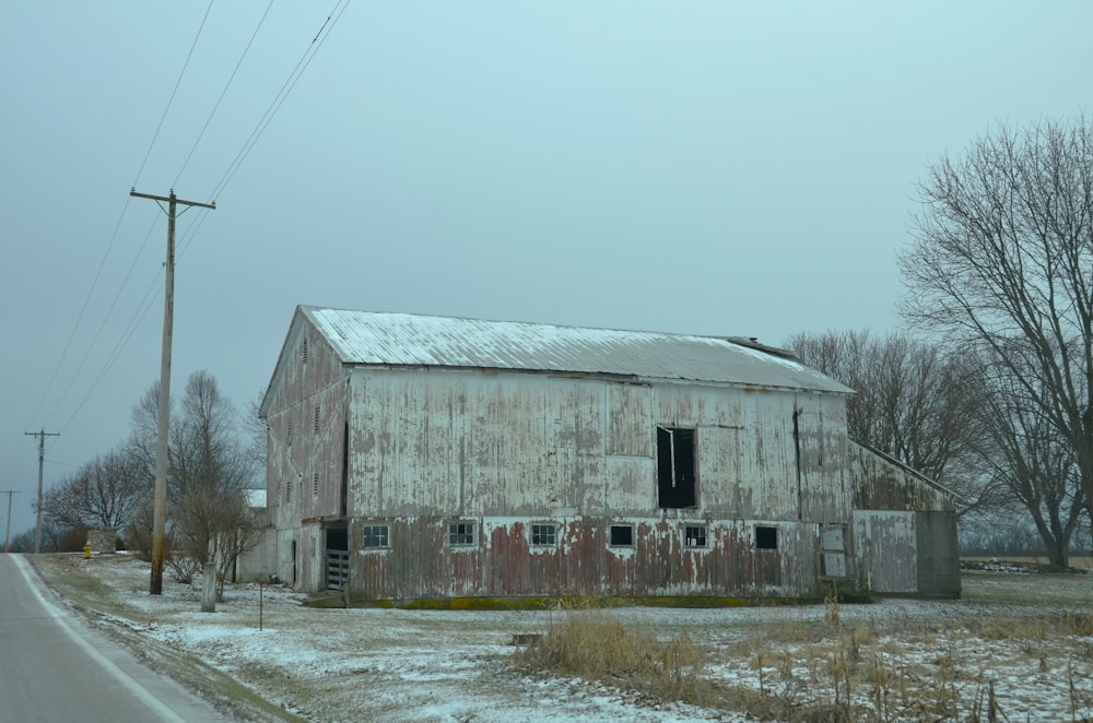 an old barn sitting on the side of a road