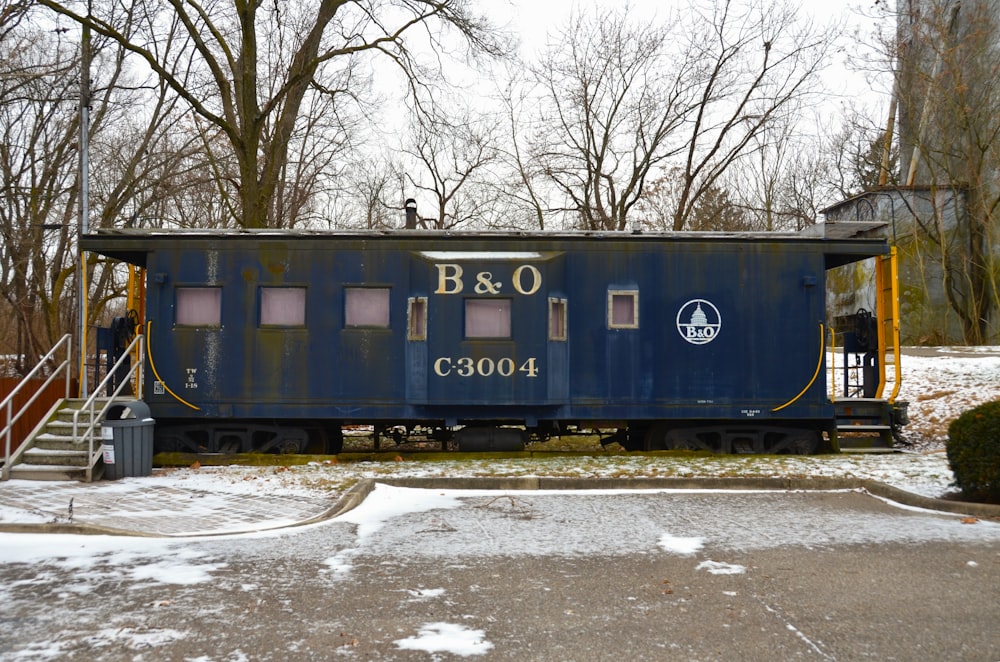 a blue train car sitting on top of snow covered ground