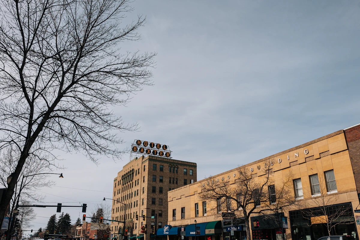 Old brick buildings and a rooftop sign in downtown Bozeman, with bare trees