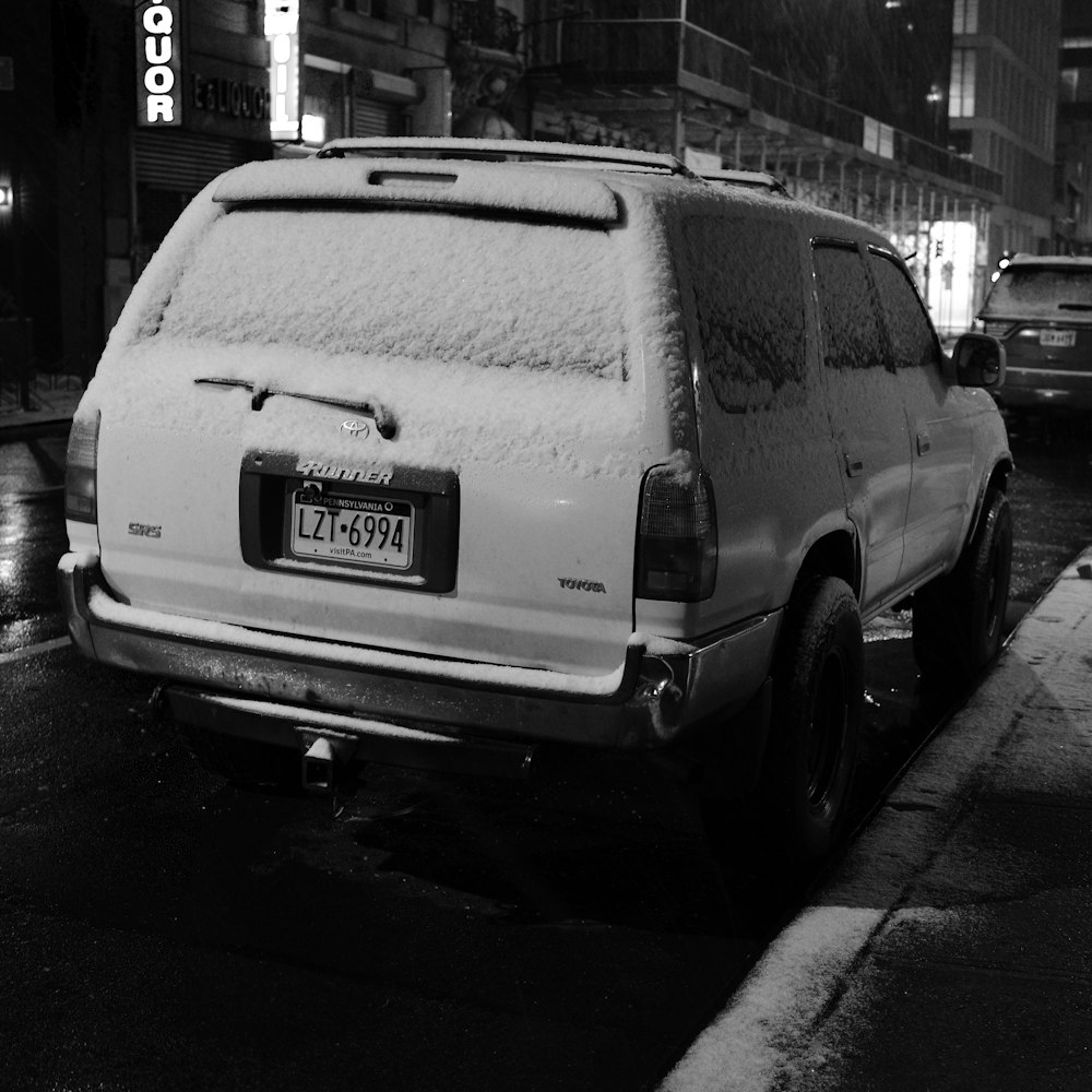a black and white photo of a car covered in snow