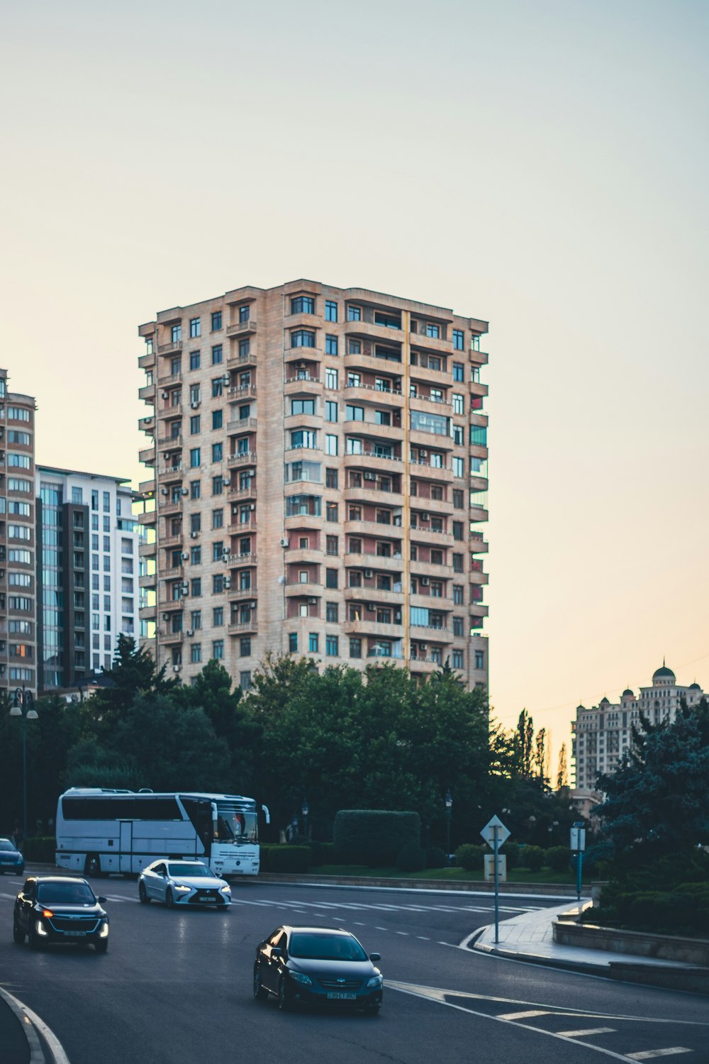 a group of cars driving down a street next to tall buildings