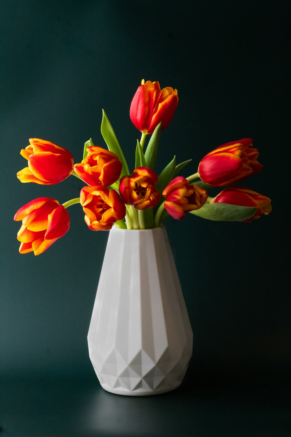 a white vase filled with red and yellow tulips