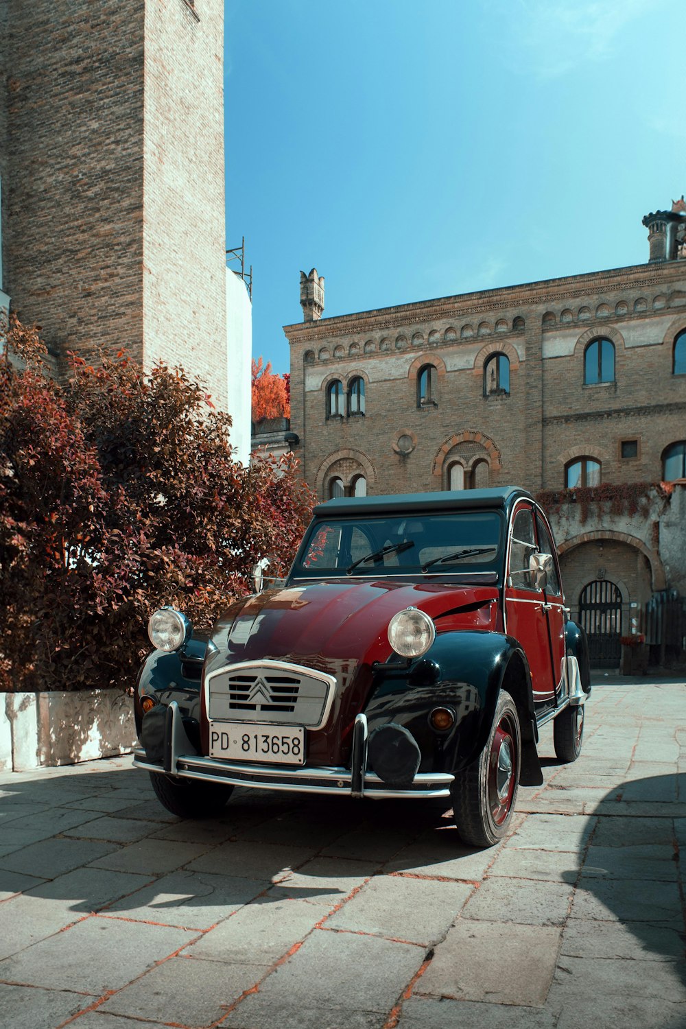 a red and black car parked in front of a building