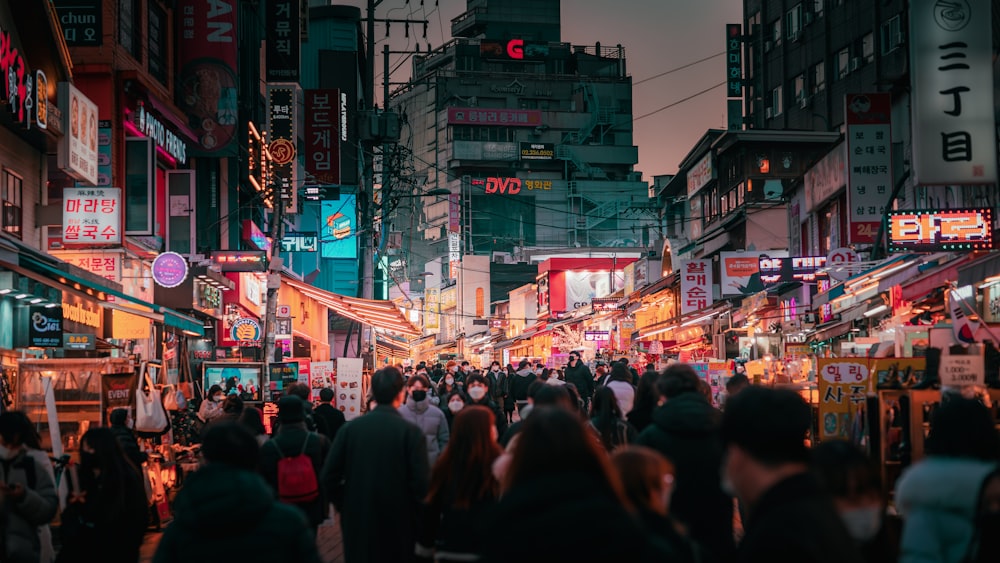 a crowd of people walking down a street next to tall buildings