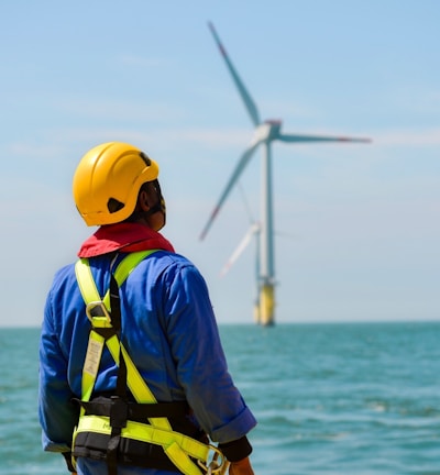 a man in a hard hat and safety gear looking at a wind turbine