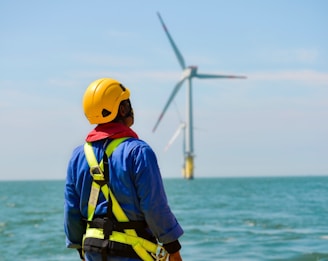 a man in a hard hat and safety gear looking at a wind turbine