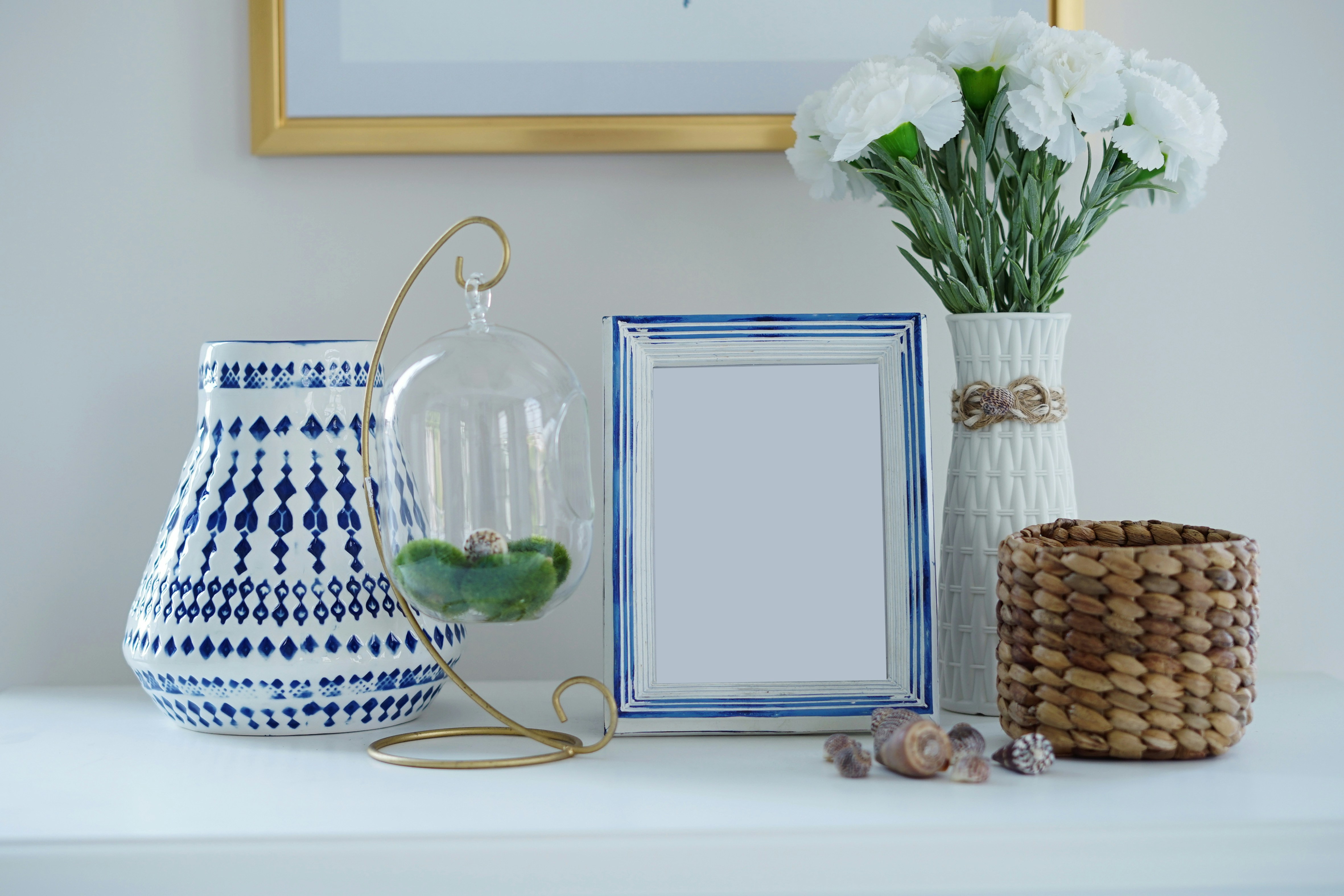 a white and blue vase with flowers and a picture frame