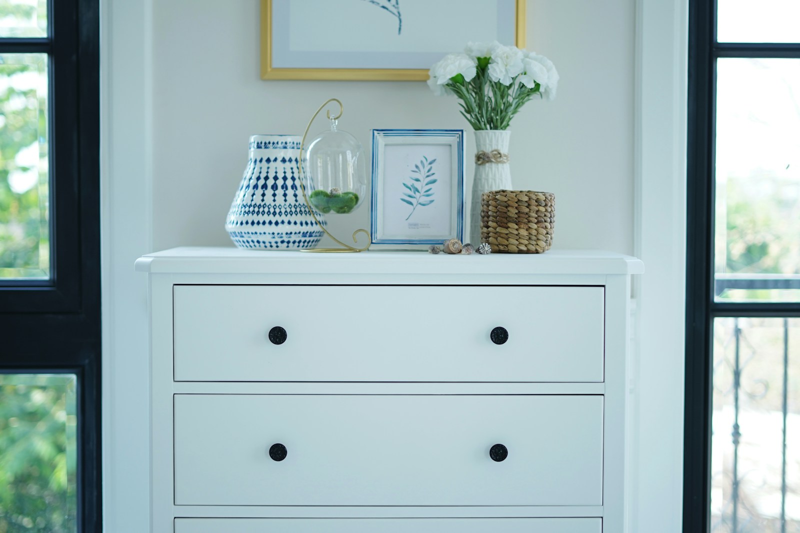 styled white dresser with art and flowers in a renter bedroom