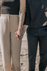 a man and a woman holding hands on the beach