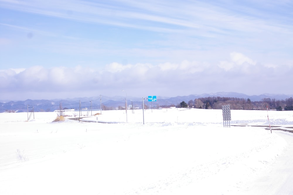a snowy field with a blue street sign in the distance