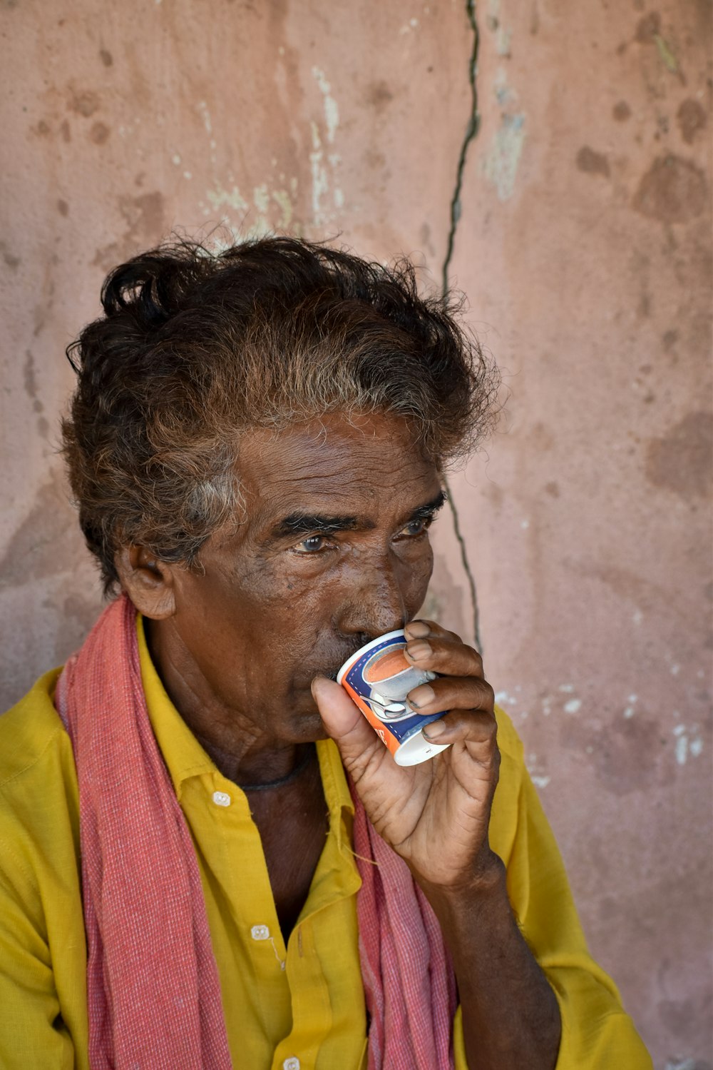 a man in a yellow shirt is drinking something