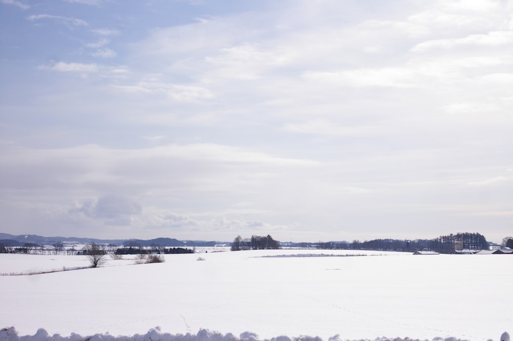 a snow covered field with trees in the distance