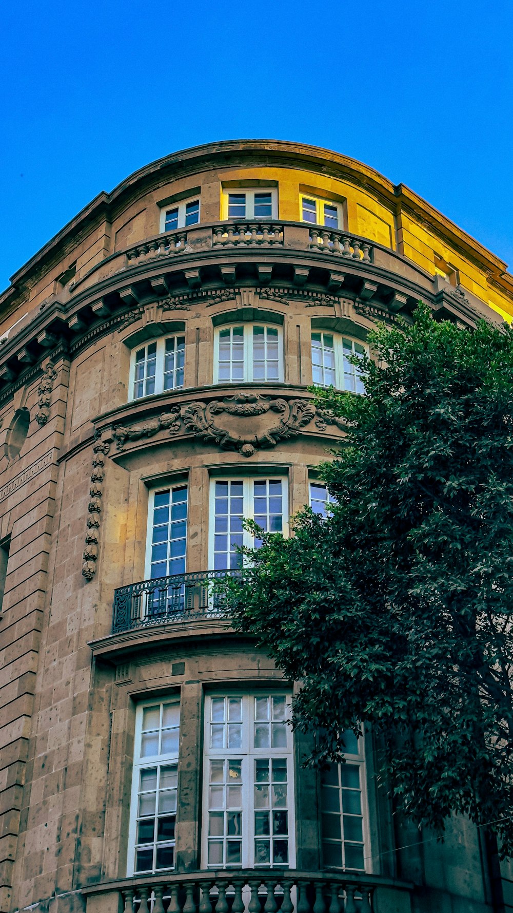 a building with a balcony and a tree in front of it