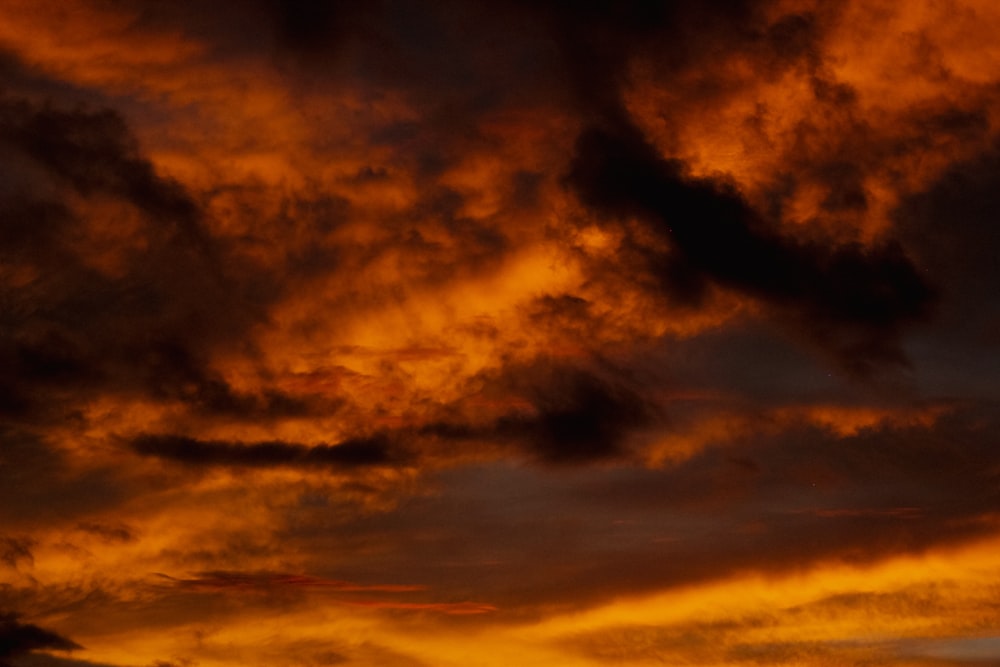 a plane flying through a cloudy sky at sunset