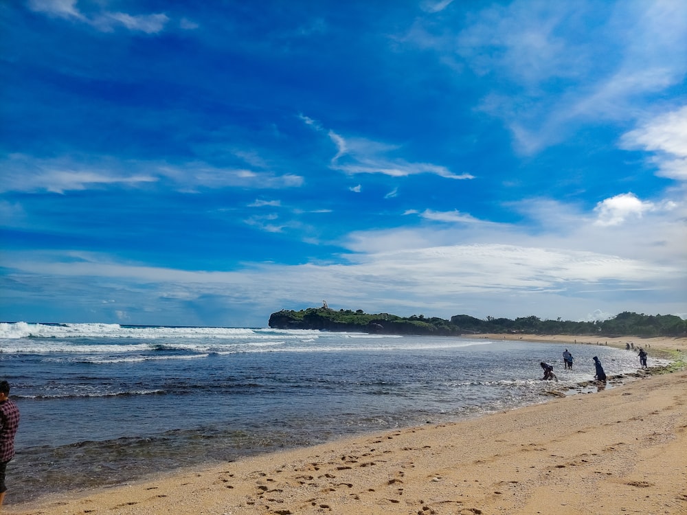 a group of people standing on top of a sandy beach