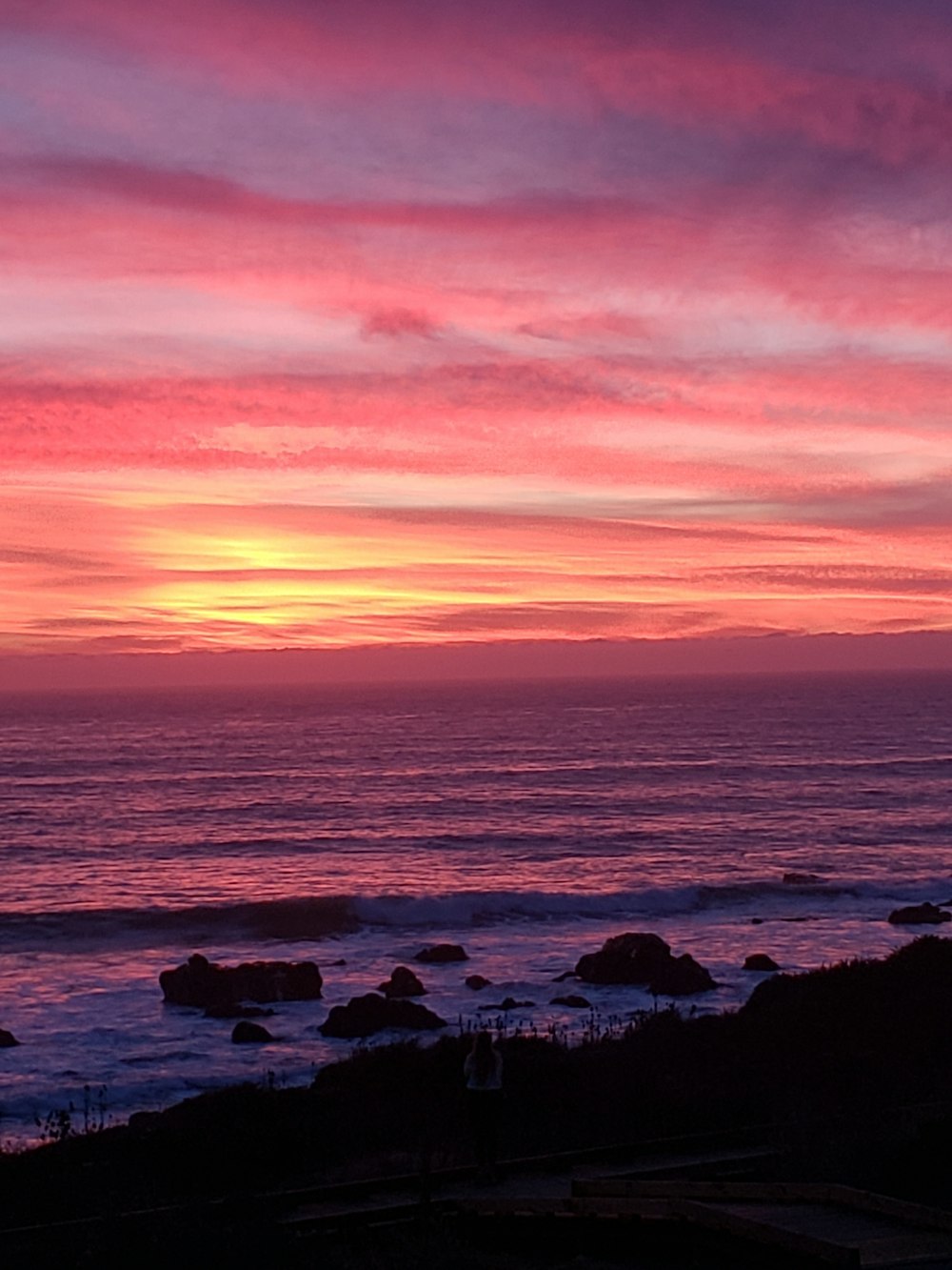 a beautiful sunset over the ocean with a lighthouse in the foreground