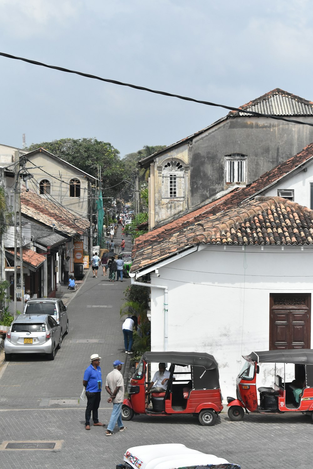 a group of people walking down a street next to a white building