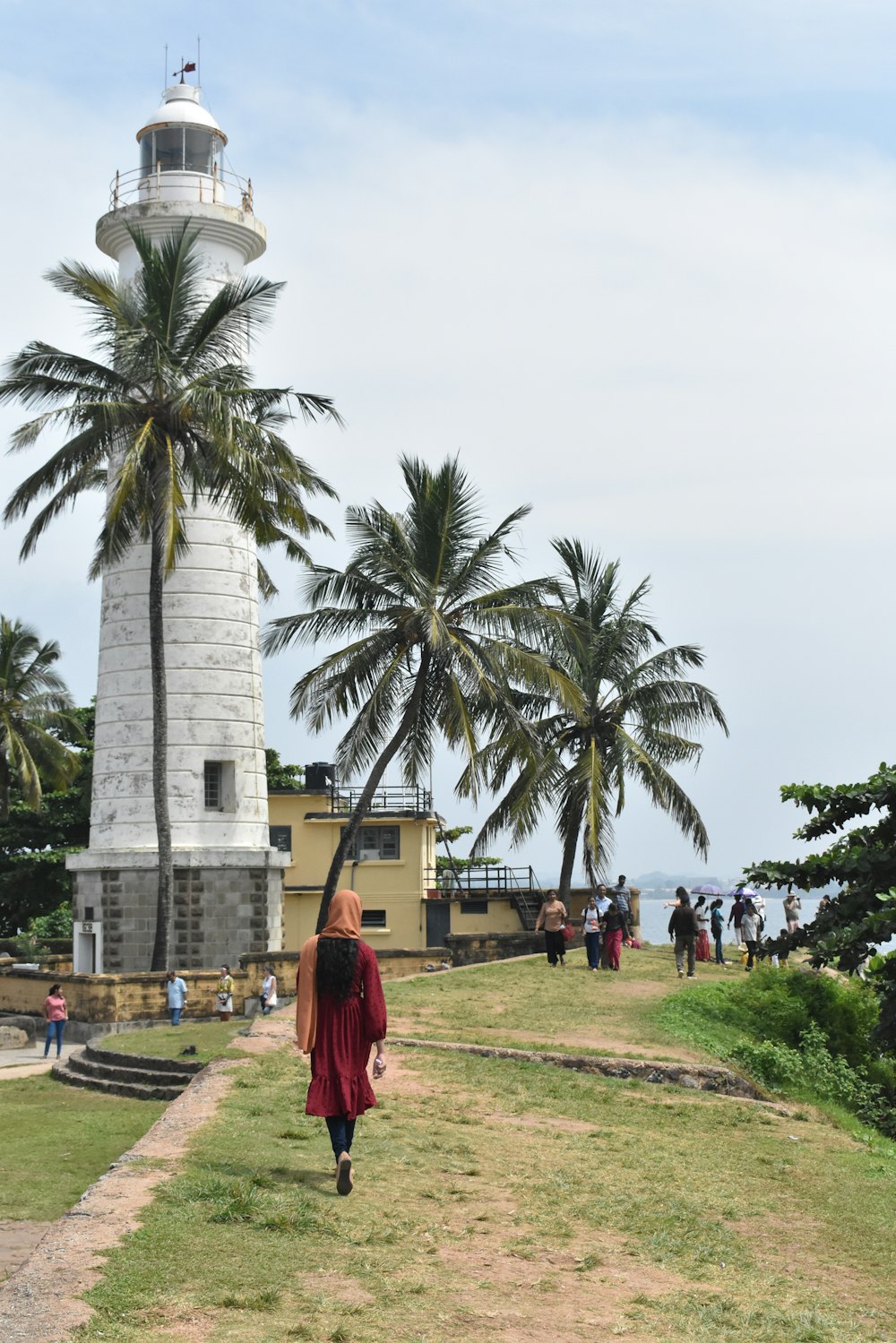 a woman in a red dress walking towards a light house