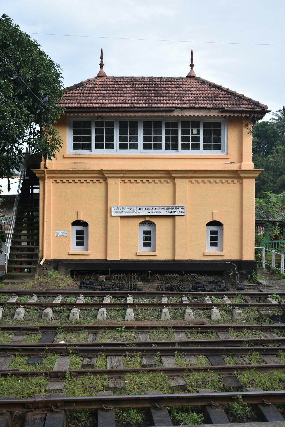 a yellow building with a brown roof sitting on top of train tracks